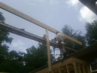 Carpenter setting a ridge beam over a new addition frame — Ice Dam Removal by Roofing Brothers in Calera