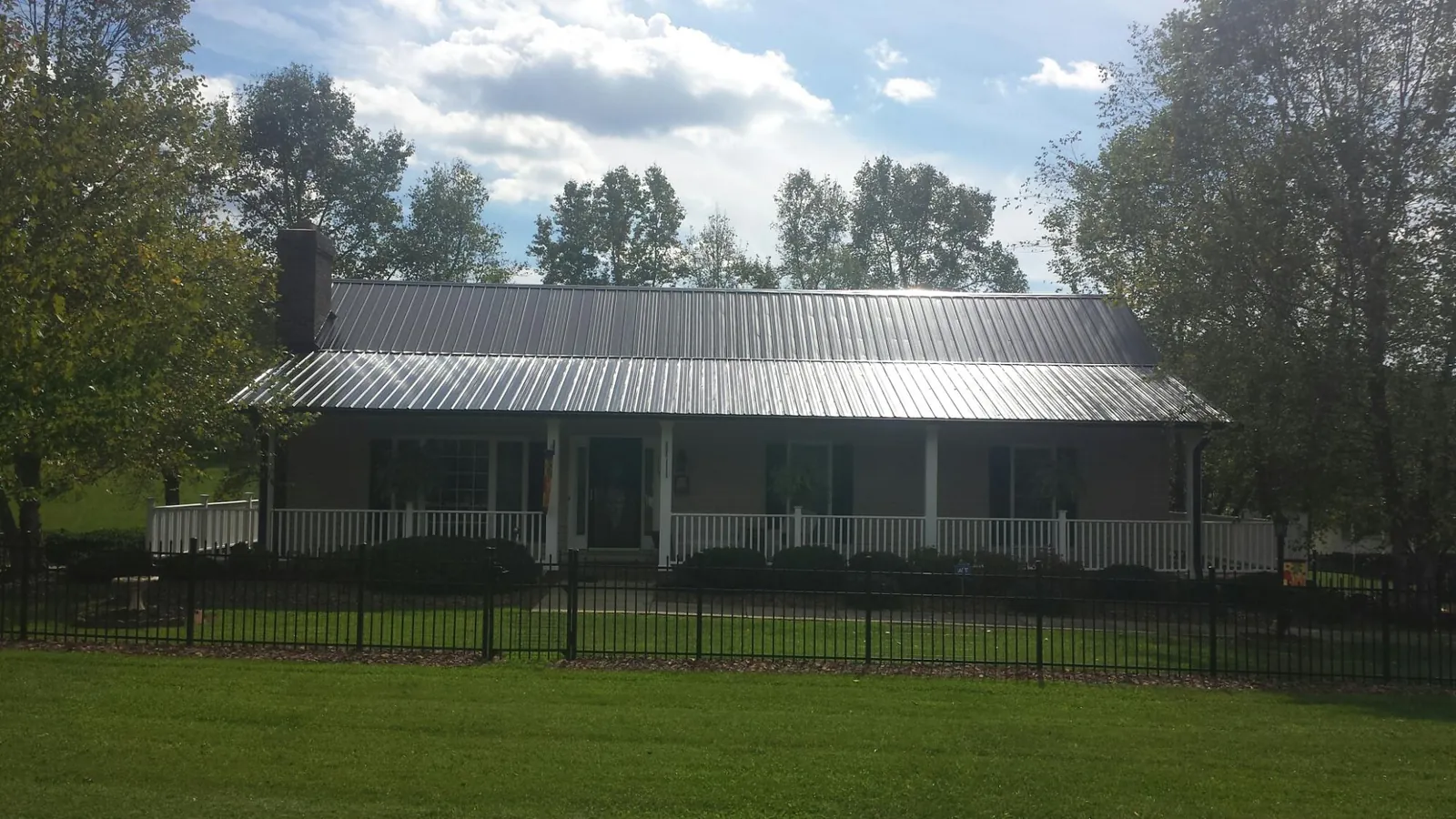 Gray metal roof on a brick ranch with a full width front porch — Gutter Guard Installation work by our crew in Calera